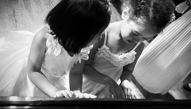 two little gilrs practicing piano together