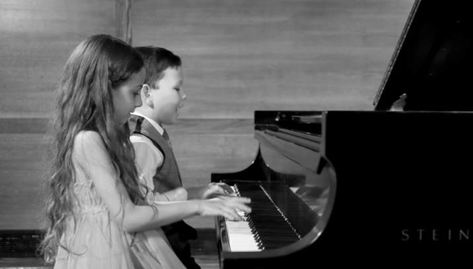 two children playing piano at recital